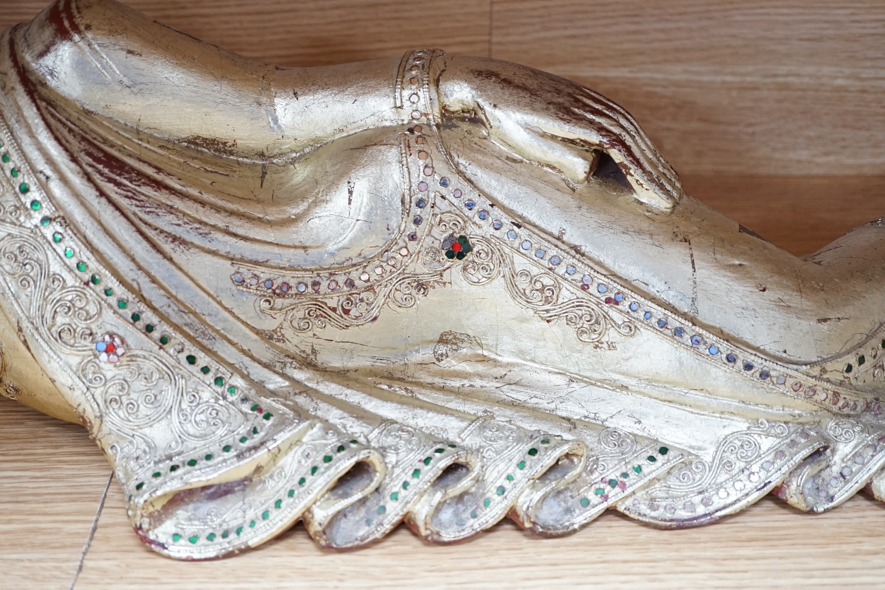 A 20th century Thai giltwood reclining figure with inset coloured glass decoration, 78cm long
